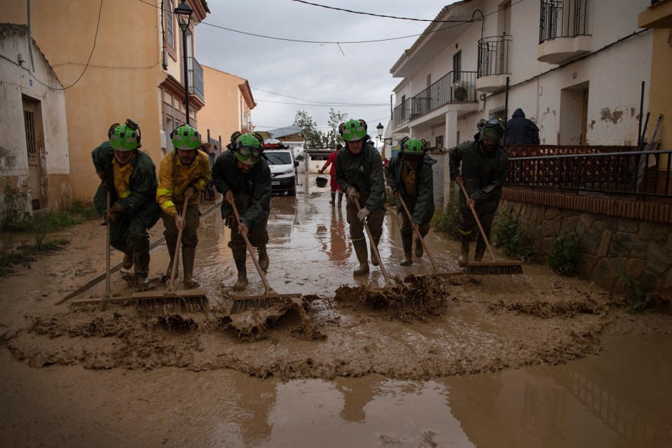 Workers try to clean up water left behind from the flooding