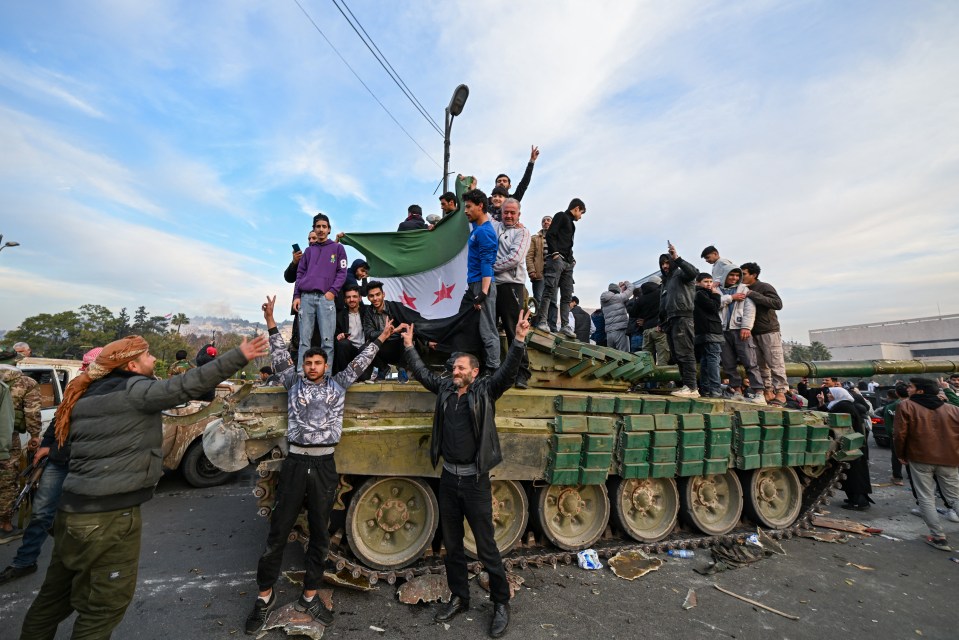 People celebrate on a tank in the centre of Damascus