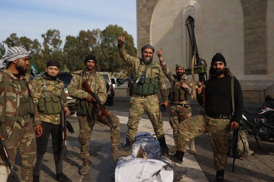 Rebel fighters pose for a picture outside the mausoleum of Syria’s late president Hafez al-Assad