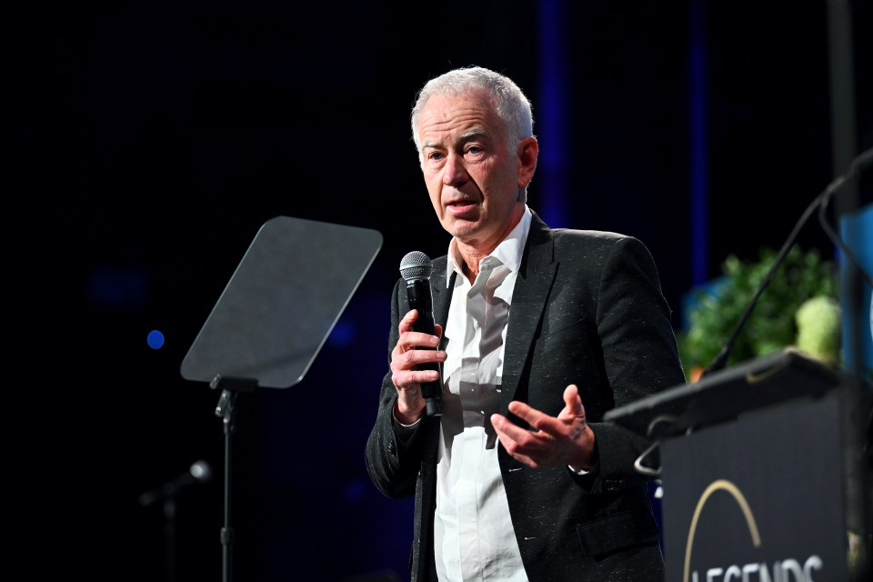 John McEnroe speaking at a podium.