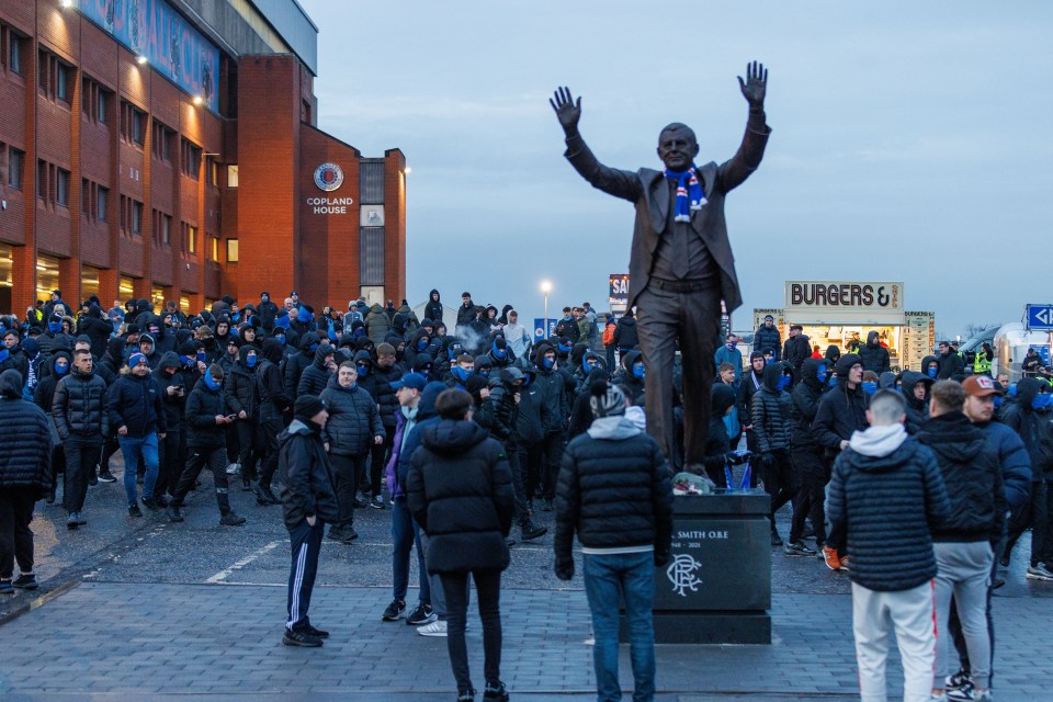 Rangers fans leaving Ibrox Stadium, passing a statue of Walter Smith.