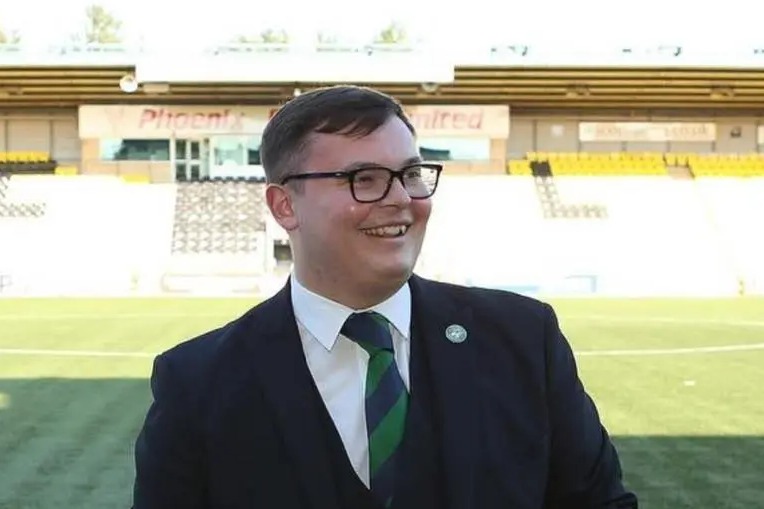 a man in a suit stands in front of a phoenix united sign